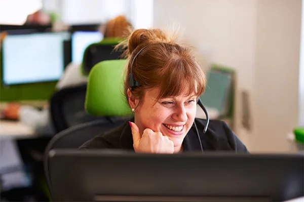 A customer service agent smiles as she talks to a customer with the aid of an interpreter